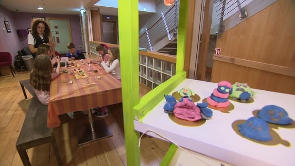 Children doing arts and crafts at a table with some fun creations in the foreground.