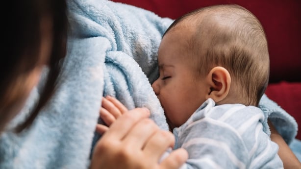 Mother breastfeeding her baby on the sofa