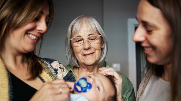Grandmother looking at her newborn grandson in the arm of his mother 