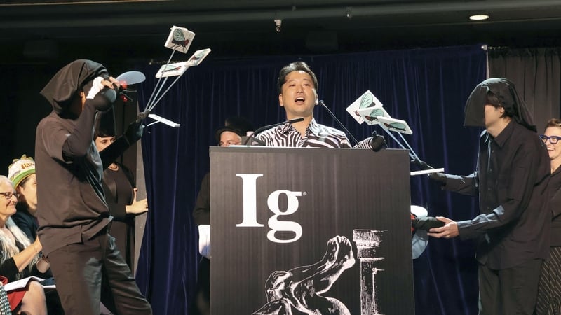 Tomoki Kojima accepts his team's award while his colleagues buzz flies around him - until he took off his jacket to reveal a zebra-striped shirt