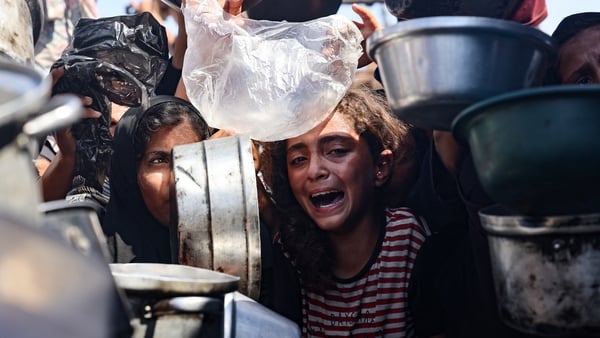 A young girl reacts as displaced Palestinians elbow their way in front of a community kitchen in Khan Younis