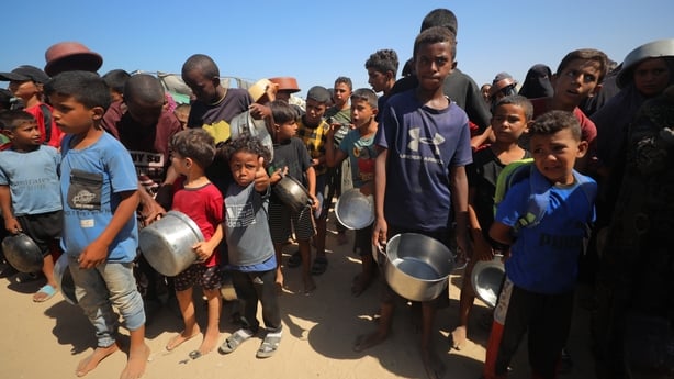 Groups of children in Gaza are seen carrying pots and pans as they wait for food