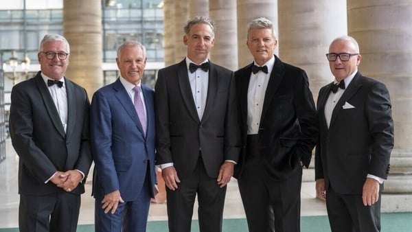 Five men in suits pose for a photo