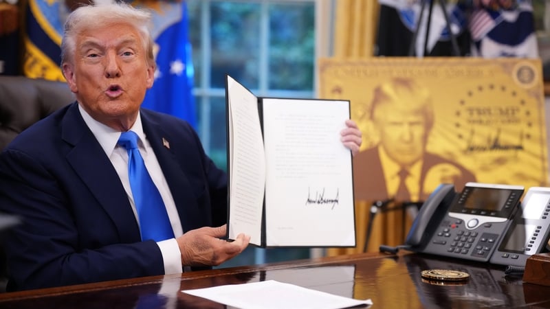 President Donald Trump holds up an executive order establishing the 'Trump Gold Card' as he introduces a $100,000 fee for H-1B visas