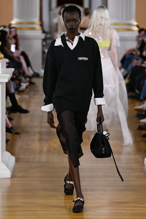 A model wears an all-black outfit with a shirt and collar on the Simone Rocha runway
