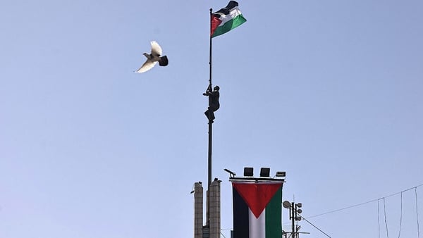 Palestinian flags raise over a tower in Ramallah in the occupied West Bank
