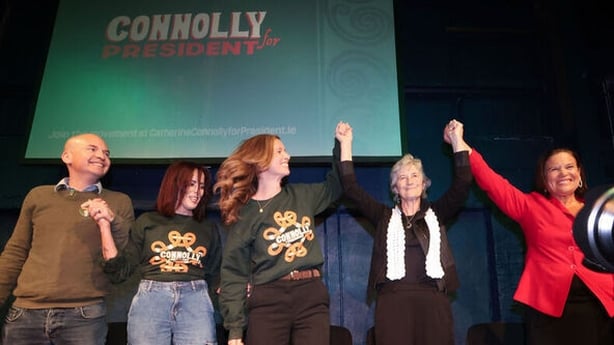 Opposition party representatives raise their arms in support of Catherine Connolly's presidential election camapign