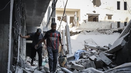 Palestinian residents inspect the area among destroyed buildings following Israeli attack on Al-Shati refugee camp in Gaza City