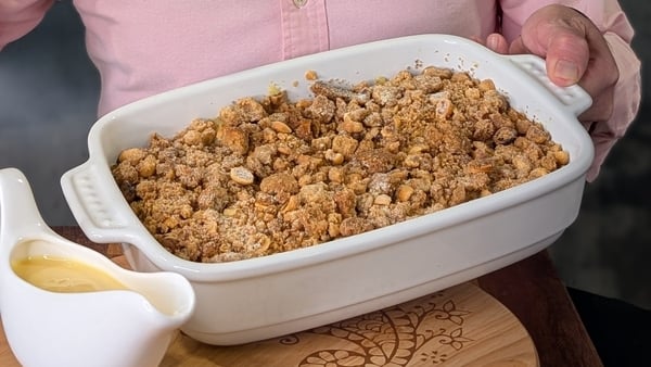A dish of crumble with a jug of custard on the side