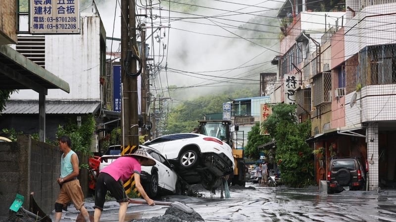 Residents clear mud from their property, while damaged cars are seen in the background, in Hualien
