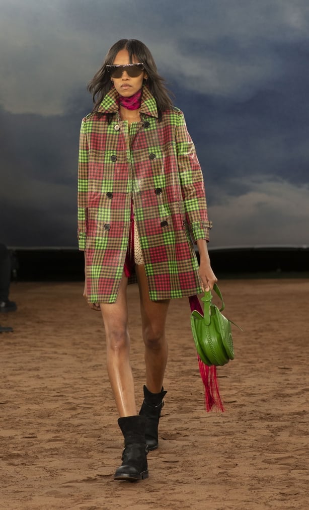 A woman wearing a plaid coat walking on a runway