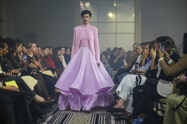 A model wearing a pale purple skirt with a pink top and cardigan