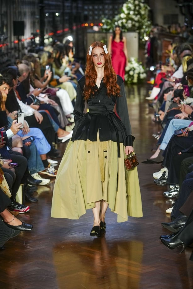 A model wearing a green skirt and dark jacket