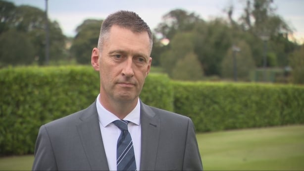 Garda Commissioner Justin Kelly standing in front a hedge.