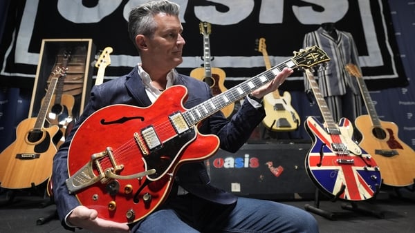 Propstore CEO Stephen Lane, holds Noel Gallagher's 1960 cherry red Gibson ES-355 guitar, damaged in Paris by Liam Gallagher on the night Oasis broke up and since repaired, with an estimate of �250,000 - �500,000, during a preview for the upcoming music me