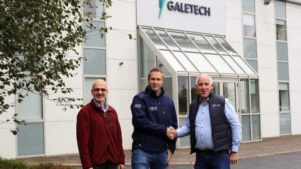 Three men outside an office building with two of them shaking hands