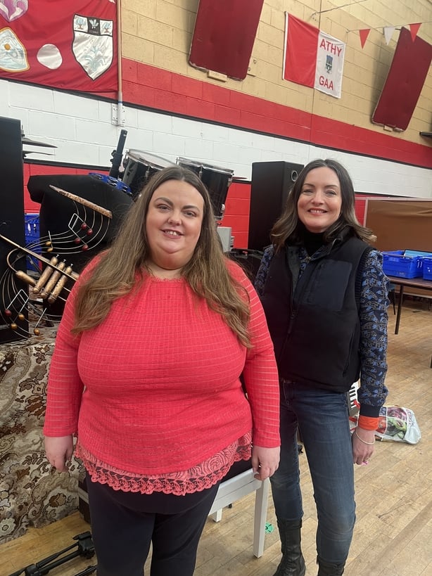A photo of three people smiling surrounded by musical instruments