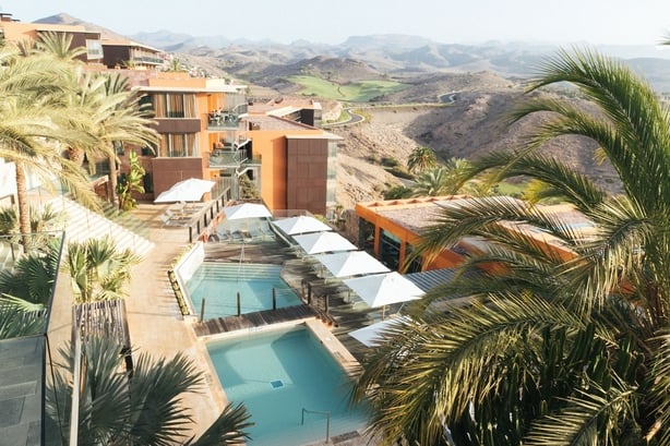 A view of a hotel with hills in the background 