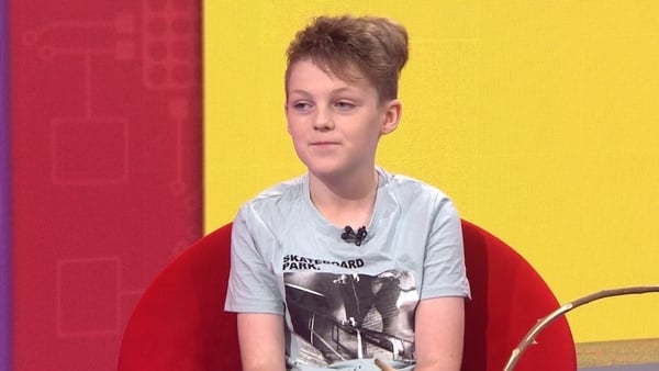 This is Art 2024 winner Uishe Delahan sitting in the news2day studio with a yellow and red background.