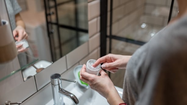 Pretty young woman with a headband using cream for moisturizing her skin