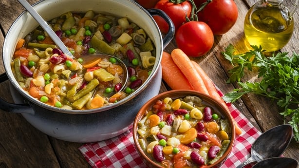 Cooking pan and bowl filled with homemade Italian Minestrone shot from above