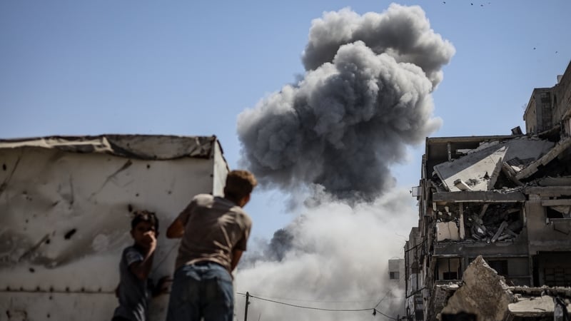Two Palestinians watch on as smoke rises following an Israeli attack in Gaza City