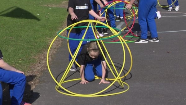 A girl climbs through a fun obstacle in the school yard.