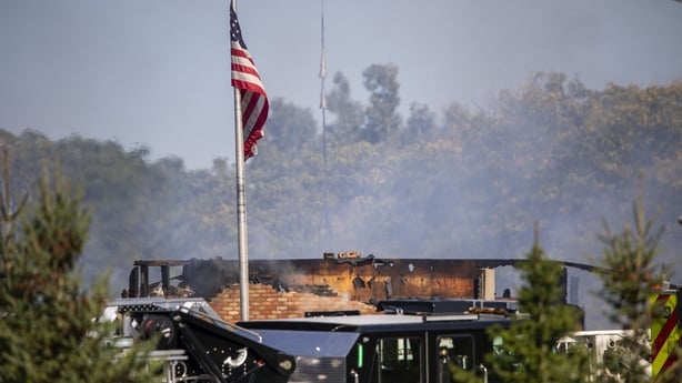 The wreckage of a building is seen under an American flag following a shooting and fire in Michigan