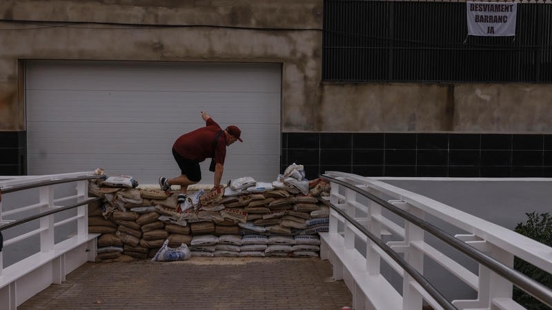 A man jumps sandbags, installed to prevent the overflow of the La Saleta ravine in Valencia, today