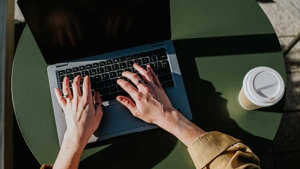 Corporate image of hands typing on a laptop keyboard in an outdoor environment, perhaps a balcony, a garden or a rooftop terrace.