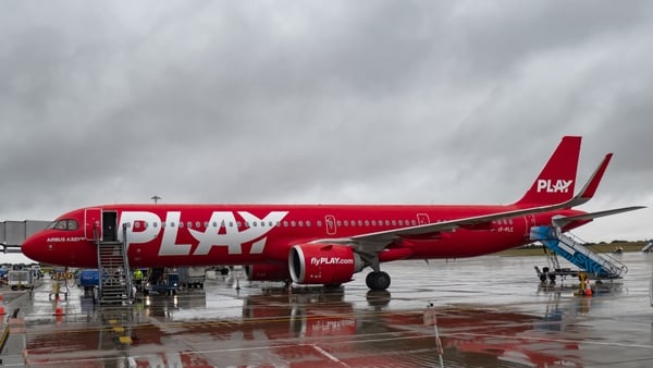 A red plane parked at an airport with the Play logo on it