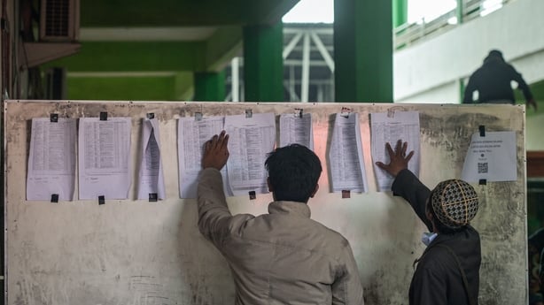 Relatives of students look at a list of names on a board as search and rescue operations continue at the Al Khoziny Islamic boarding school in Sidoarjo, East Java province after a multistorey building at the school collapsed