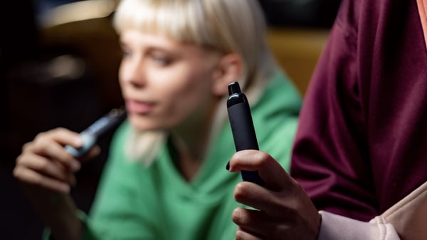 Close up of unrecognizable woman smoking electronic cigarette with her friend.