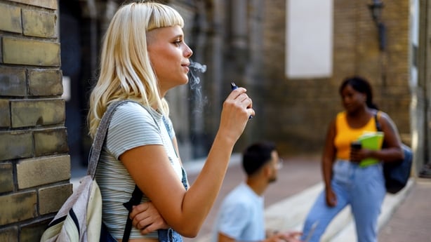  A female student discreetly uses an electronic cigarette between classes on campus