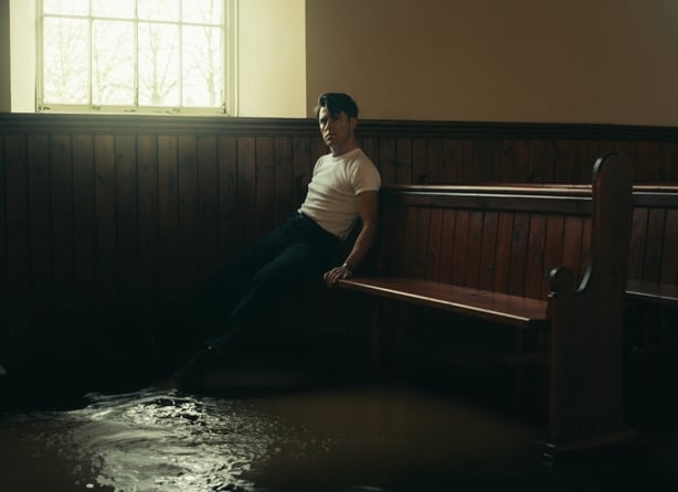 Irish singer Niall McNamee sitting on pew