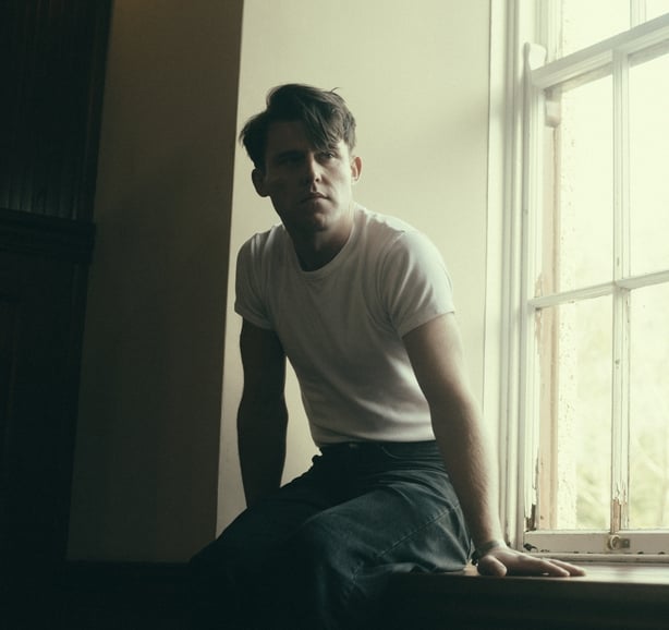 Irish singer Niall McNamee sitting by a window 