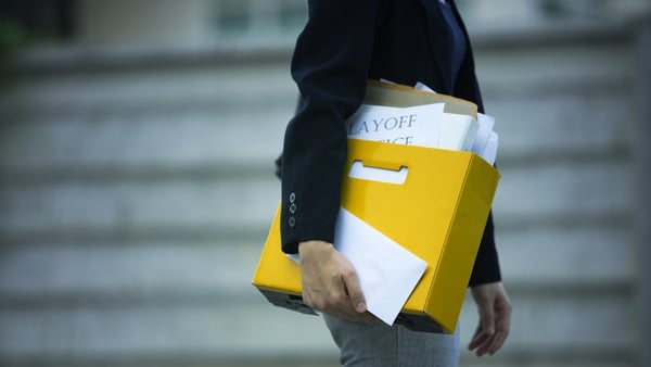 Image of a person holding a yellow file with documents saying 'lay off' on them