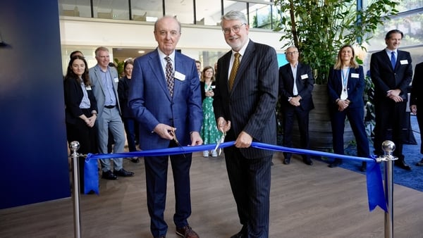 Two men dressed in suits cut the ribbon of a new industrial facility