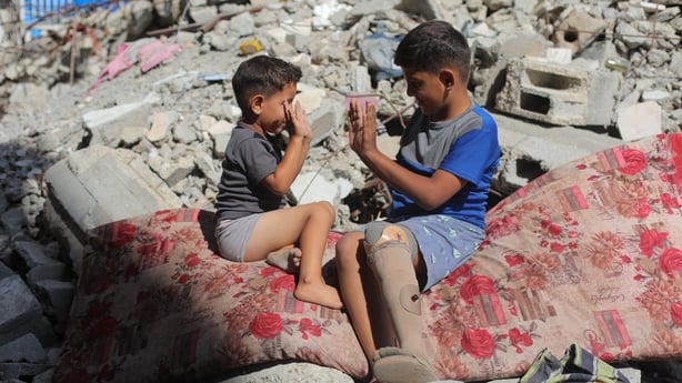 Two boys are seen playing amid rubble on the ground at the Bureij Refugee Camp in Gaza