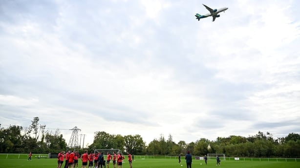 1 October 2025; Shelbourne players huddle as a flight bound for Dublin Airport comes in to land during a Shelbourne training session at the AUL Complex in Clonshaugh, Dublin. Photo by Ben McShane/Sportsfile