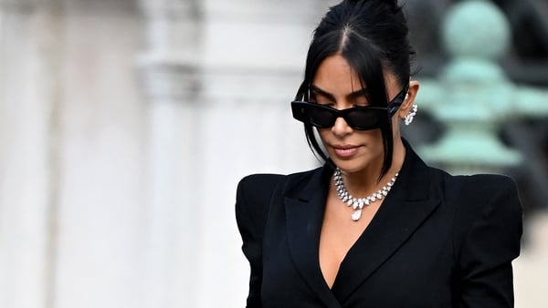 Kim Kardashian leaving court wearing a black suit and diamond necklace