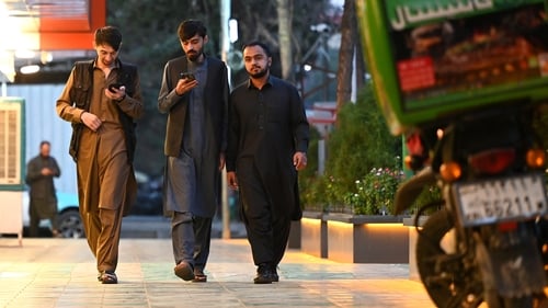 Afghan men using their mobile phones in Kabul yesterday. Online learning by teenage girls and women was stopped during the outage
