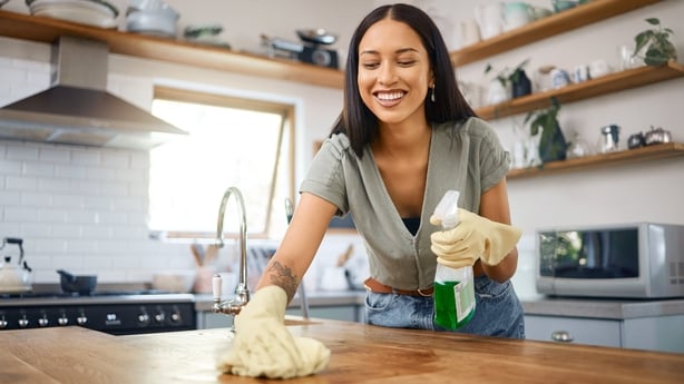 Young mixed race woman smiling while cleaning a kitchen table