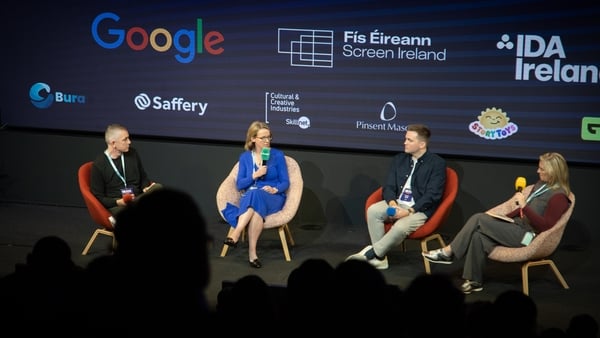 Four people with microphones on stage in front of an audience