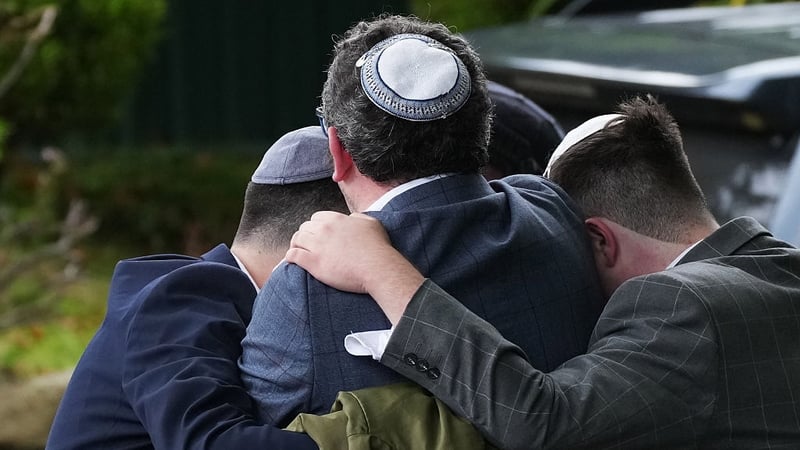 Members of the public react as they gather near the Heaton Park Hebrew Congregation Synagogue