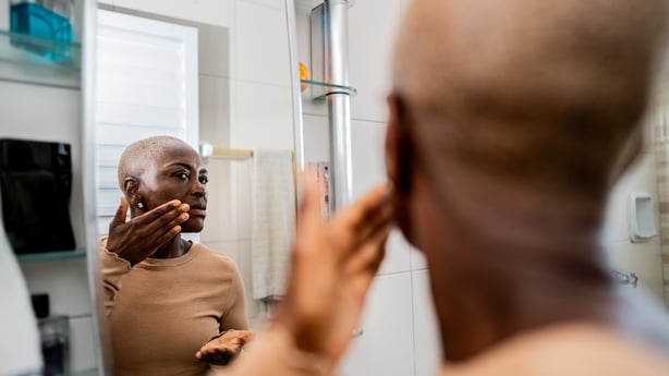 Mature woman applying face cream in the bathroom at home