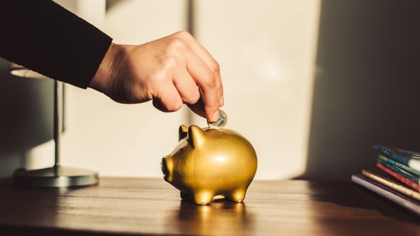 Woman putting coin into a golden piggy bank.