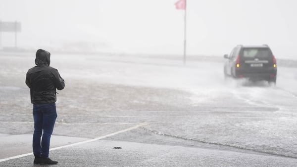 A car drives through floodwater in Galway as a man watches on