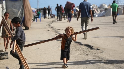 A small boy carries a piece of wood as he walks on a coastal path northwest of Nuseirat refugee camp