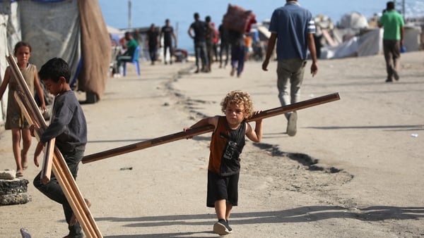 a little boy carries a large wooden plank in gaza
